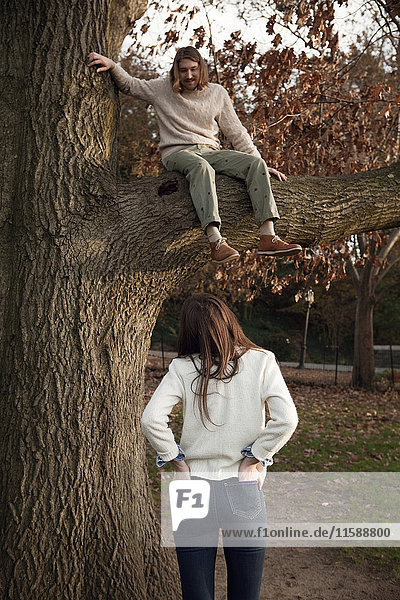 Girl looking up at boy in tree