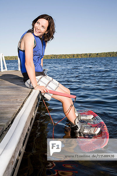 Woman sitting on dock with wakeboard