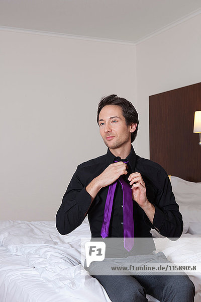 Geschäftsmann im Hotelzimmer  der seine Krawatte bindet