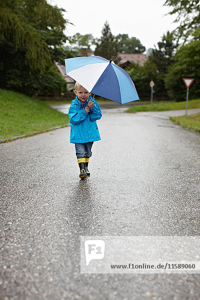 Kleinkind Junge mit Regenschirm auf der Strasse