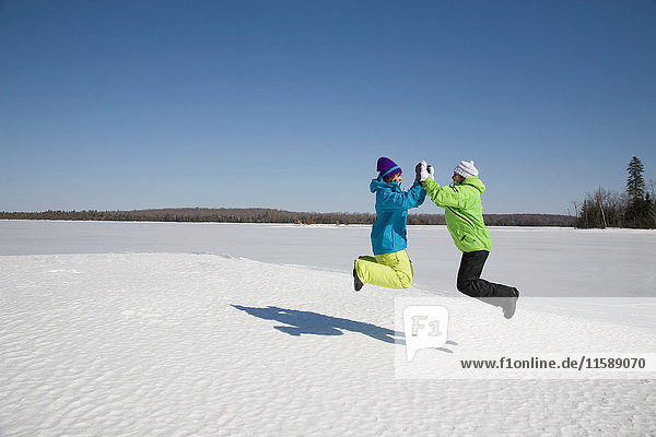 Zwei Frauen springen auf gefrorenen See