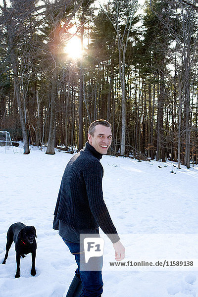 Mann mit Hund im Wald im Schnee