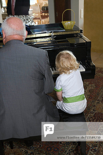 Junge spielt mit Großvater Klavier