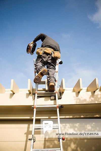 Workman on ladder to roof
