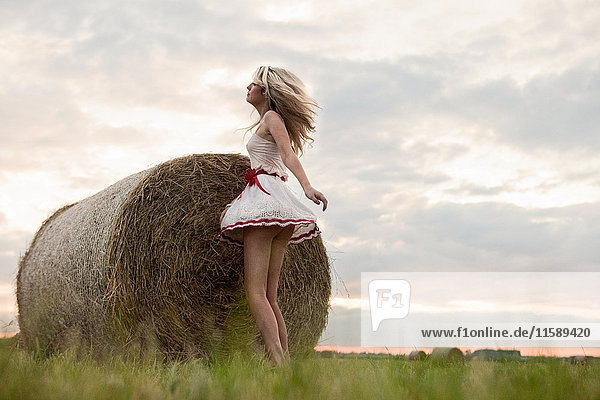 Young woman dancing by hay bale in field