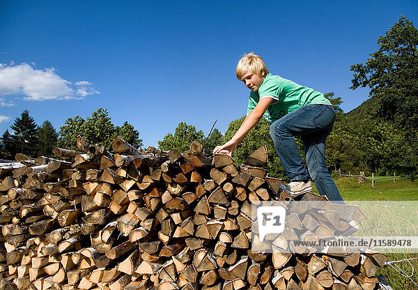 boy climbing stack of wood
