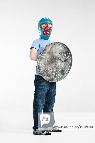 Boy wearing mask holding dustbin lid