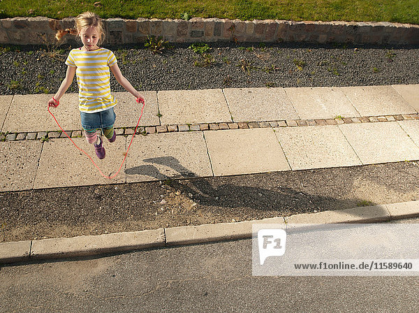 Young girl skipping on sidewalk