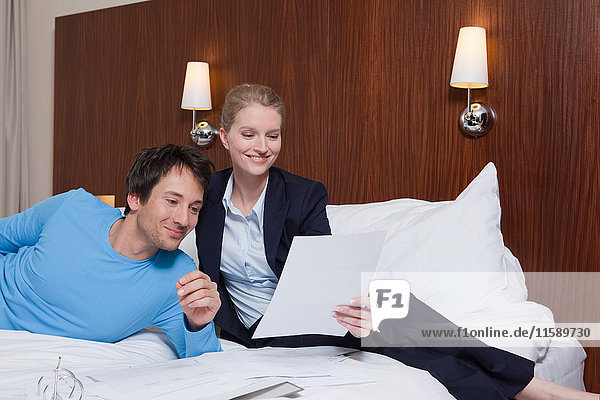 Paar im Hotelbett lesend  lachend