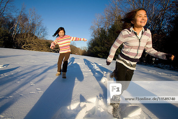 Zwei Mädchen rennen im Schnee