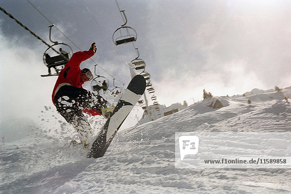 Männlich in Aktion auf einem Snowboard