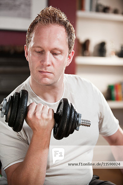 Mid adult man lifting dumb bell in home