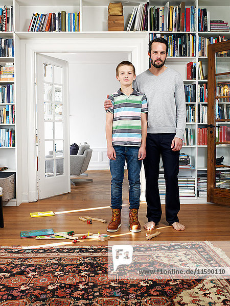 Vater und Sohn stehen zusammen im Wohnzimmer  Porträt
