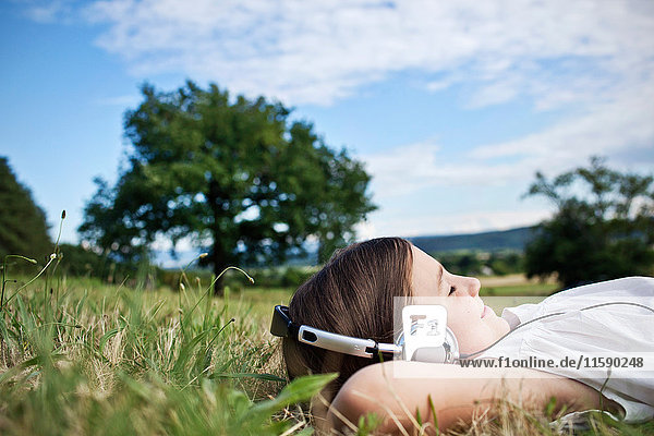 Girl in headphones laying in grass