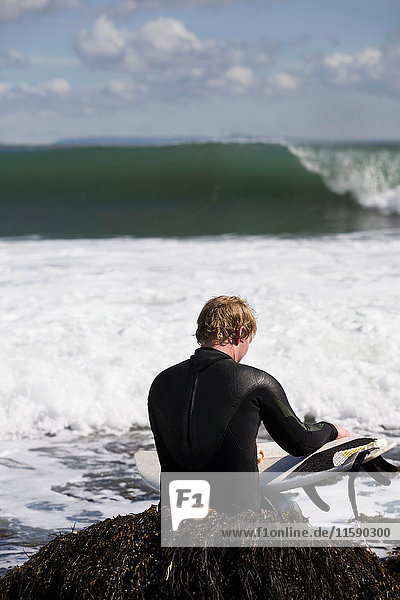 Surfer sitting on seaweed in waves