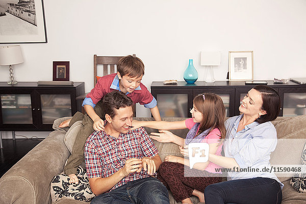 Family of four relaxing together on sofa