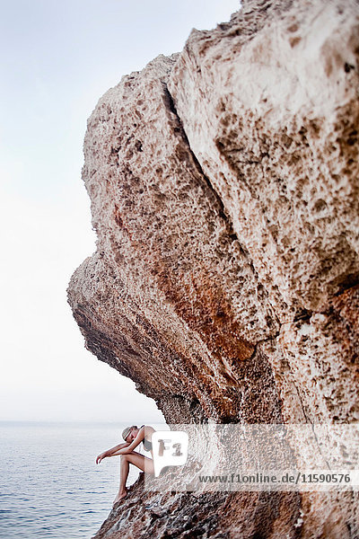 Frau  die auf den Felsen an Klippen sitzt