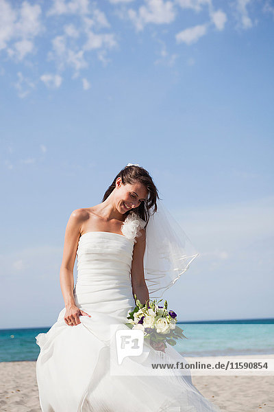 Braut hält den Brautstrauss am Strand