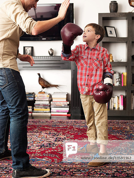 Vater lehrt den Sohn im Wohnzimmer zu boxen