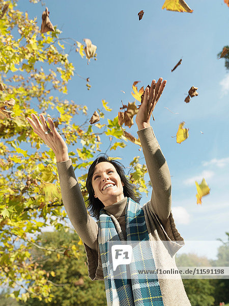 Frau mit Herbstlaub in der Luft