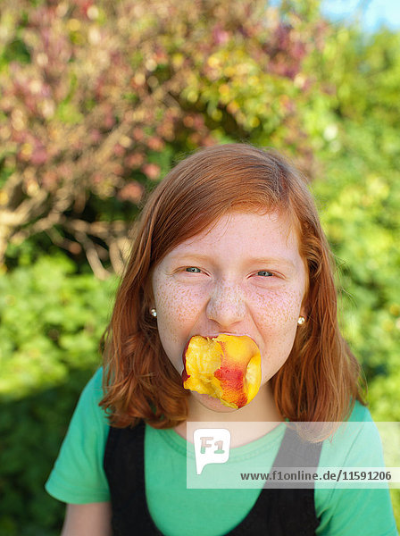 Young girl holding peach in mouth  portrait