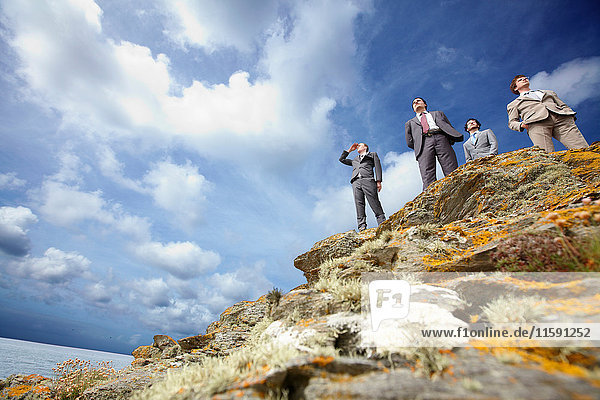Businessmen standing on cliff edge