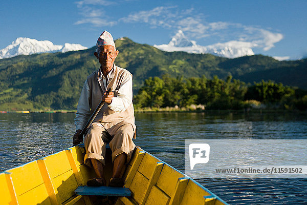 Nepalesischer Mann rudert traditionelles Boot