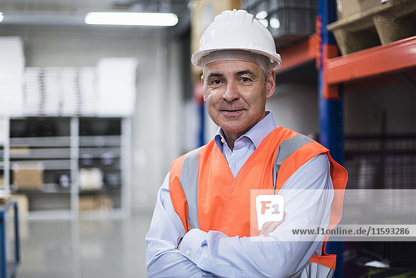 Portrait of man in factory hall wearing safety vest and hard hat