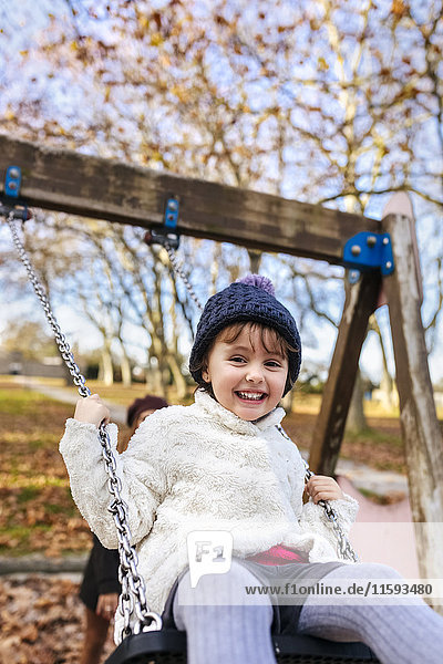 Portrait of happy little girl on a swing