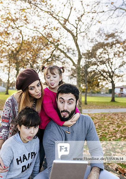 Family with tablet in autumnal park