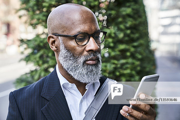 Mature businessman reading smartphone messages