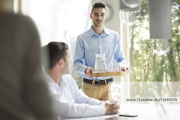 Young man serving water at a business meeting