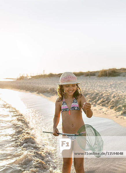 Spain  Menorca  happy girl with a dip net on the beach