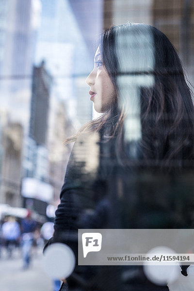 USA  New York City  Manhattan  daydreaming young woman behind glass pane