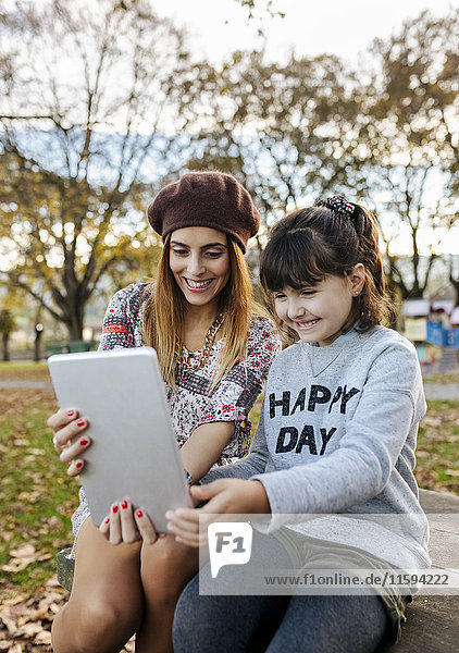 Mutter und kleine Tochter nehmen Selfie mit Tablette im herbstlichen Park