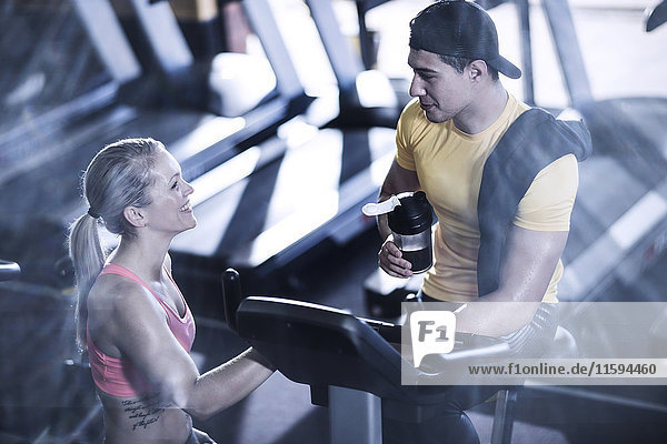 Junger Mann und Frau sprechen im Fitnessstudio