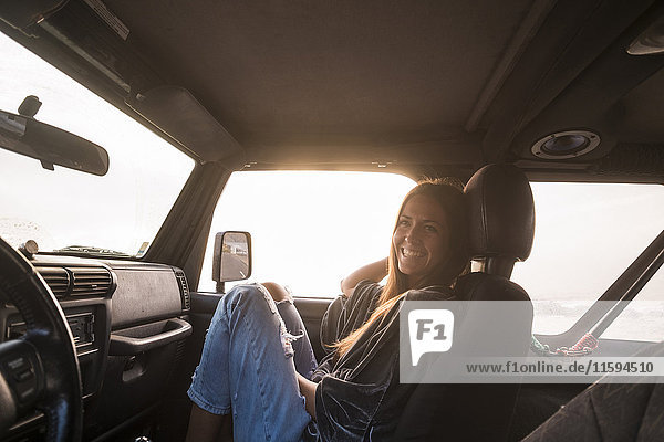 Lachende Frau bei Sonnenuntergang im Auto sitzend