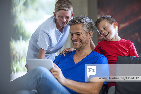 Kinder  die mit ihrem Vater auf einem digitalen Tablett suchen