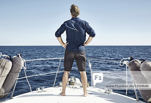 Back view of mature man standing on his motor yacht with hands on hips