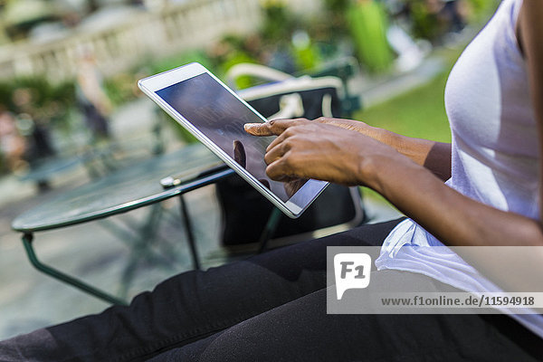 Woman sitting in a park using tablet  partial view