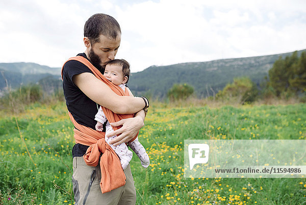 Father carrying baby girl outdoors in a baby sling
