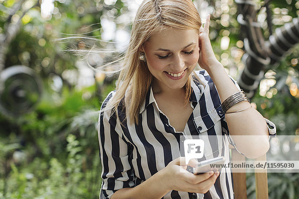 Happy blond woman looking at her smartphone