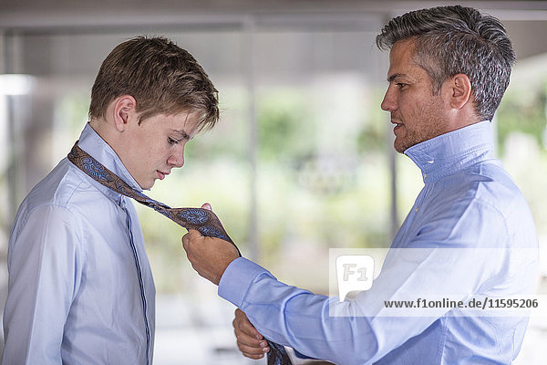 Vater hilft dem Sohn beim Binden seiner Krawatte