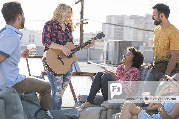 Freunde bei einer Dachparty und Gitarre spielen