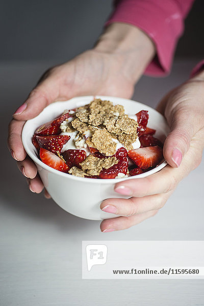 Woman holding bowl with muesli  yogurt and strawberries