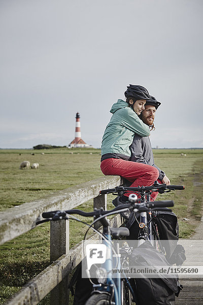 Germany  Schleswig-Holstein  Eiderstedt  couple on bicycle trip having a break near Westerheversand Lighthouse