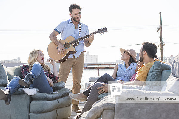 Freunde bei einer Dachparty und Gitarre spielen