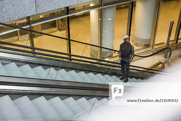 Young man standing on escalator looking around