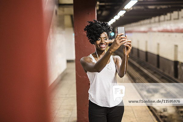 USA  New York City  Manhattan  smiling woman taking selfie at subway station platform