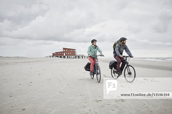 Germany  Schleswig-Holstein  St Peter-Ording  couple riding bicycle on the beach